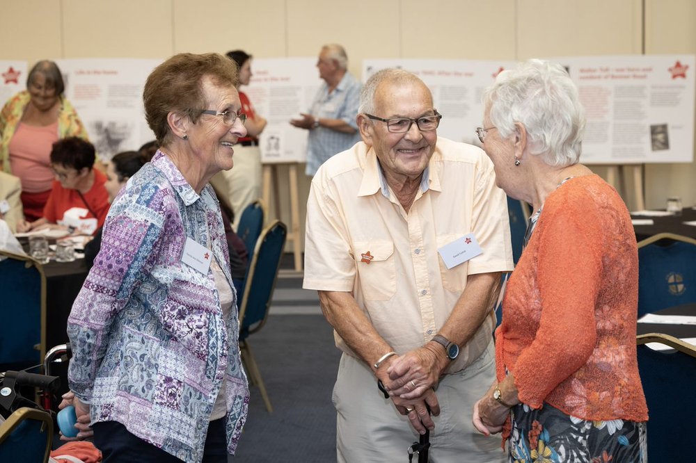 Two elderly ladies and one gentleman chatting indoors at Action for Children's Annual Reunion