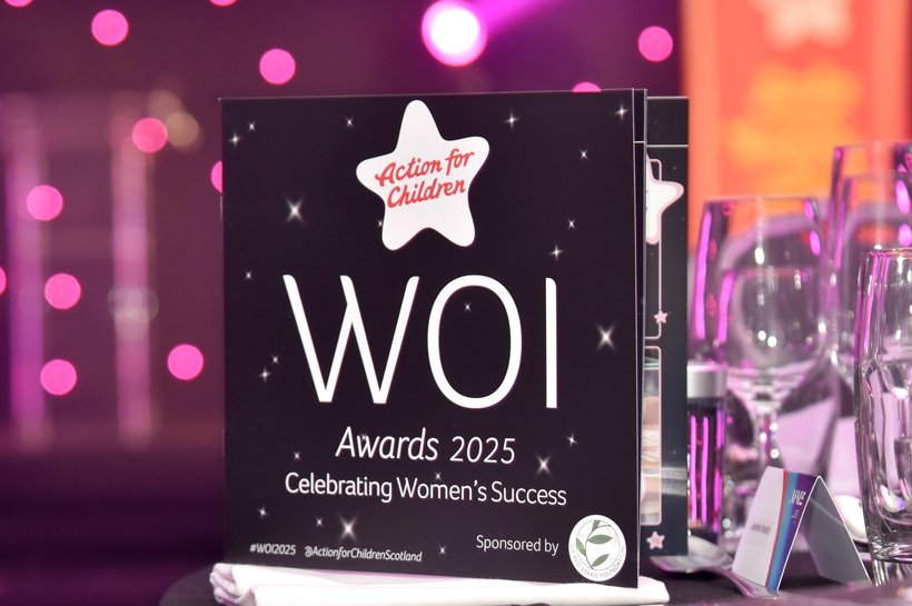 Women of Influence 2025 event programme on a table with glasses and napkins