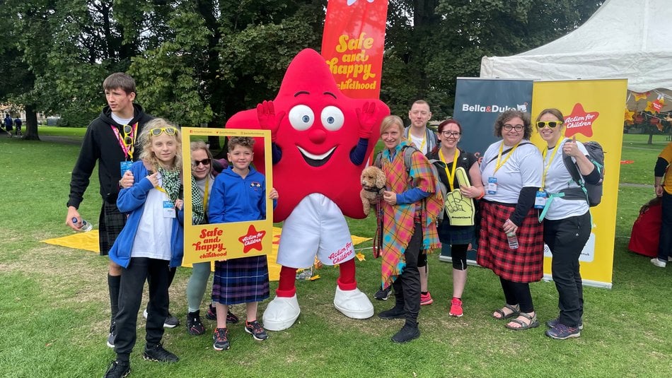 Action for Children mascot Cosmo poses with happy Kiltwalkers
