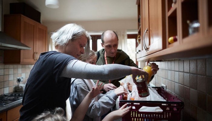 Family of four reaching into a food delivery package from Action for Children
