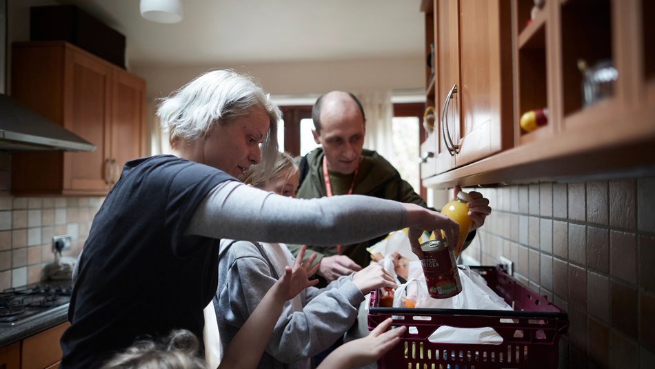 Family of four reaching into a food delivery package from Action for Children