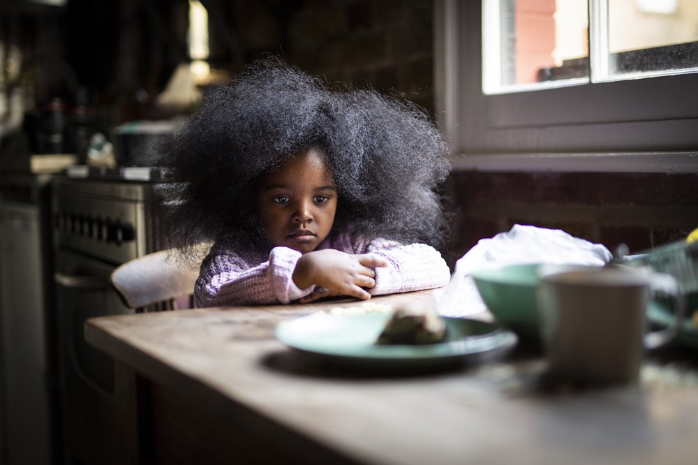 Alice a hunry sad girl sits at a table looking at empty plates