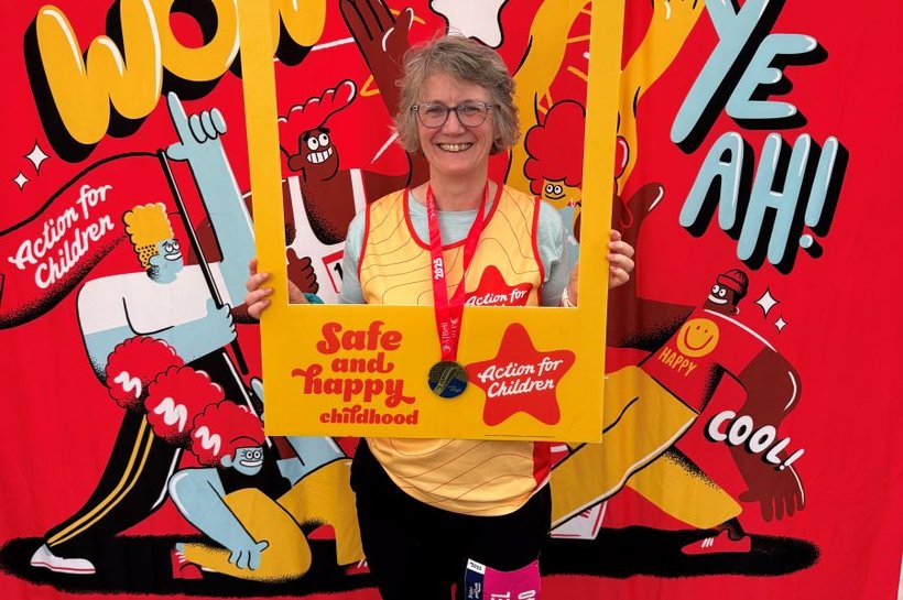 Bath Half Marathon Runner holding an Action for Children photo frame and smiling.
