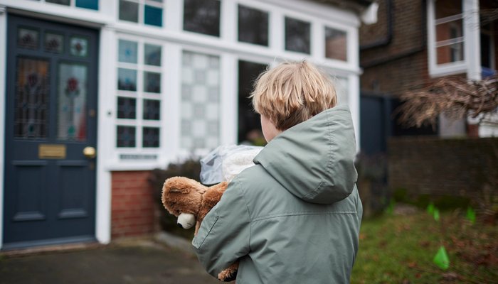 Boy carrying teddy approaching house