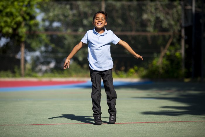 Boy doing a star jump in school uniform