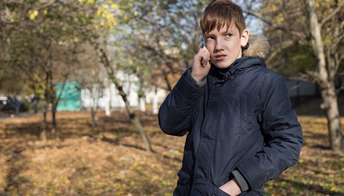 Boy standing outside in a garden on the phone to someone