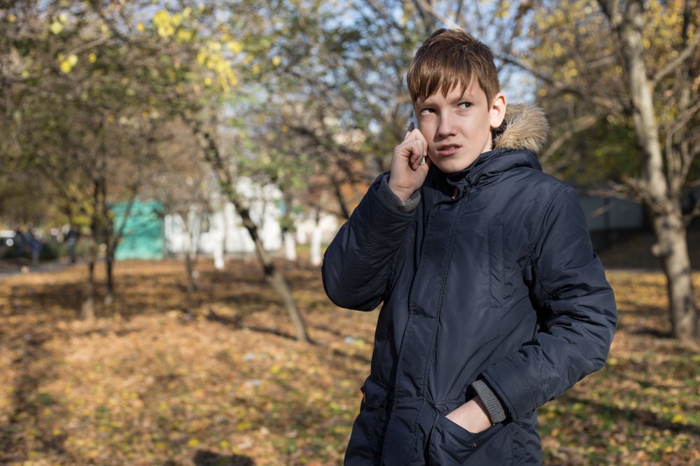 Boy standing outside in a garden on the phone to someone