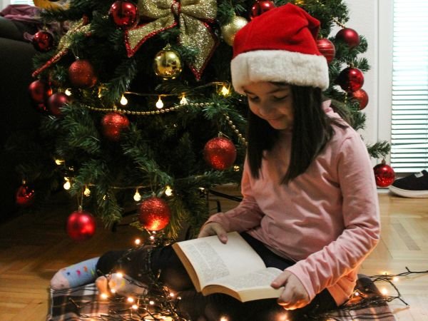 Child reading in front of Christmas tree