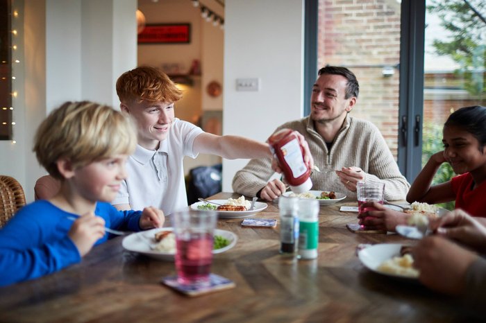 Children in care having breakfast with their carer and smiling