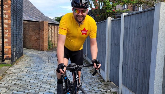 Cyclist on bike wearing an Action for Children cycling jersy