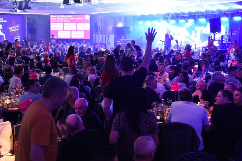 A ballroom full of people sat round tables taking part in a music quiz
