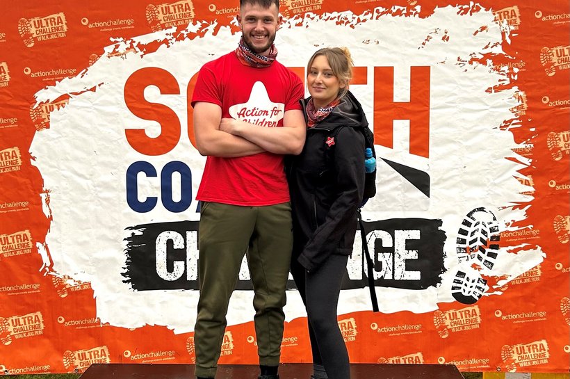 Emily Blyth and friend posing in front of South Coast ultra challenge poster