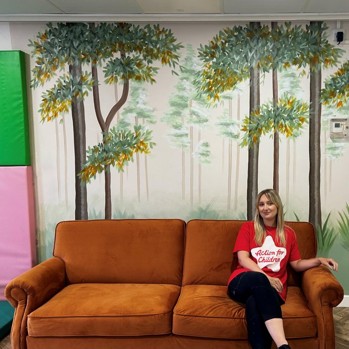 Emily Blythe sitting on sofa in front of wall she has decorated