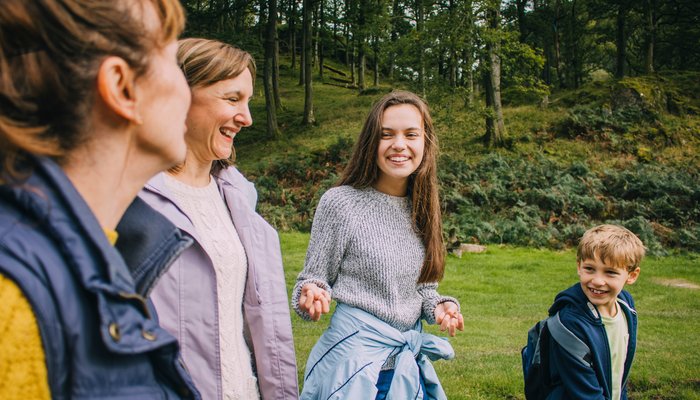 Family happily talkng and smiling as they walk outdoors in the woods