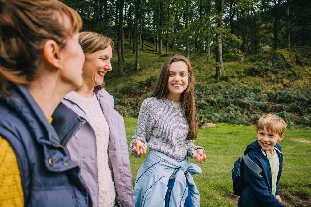 Family happily talkng and smiling as they walk outdoors in the woods