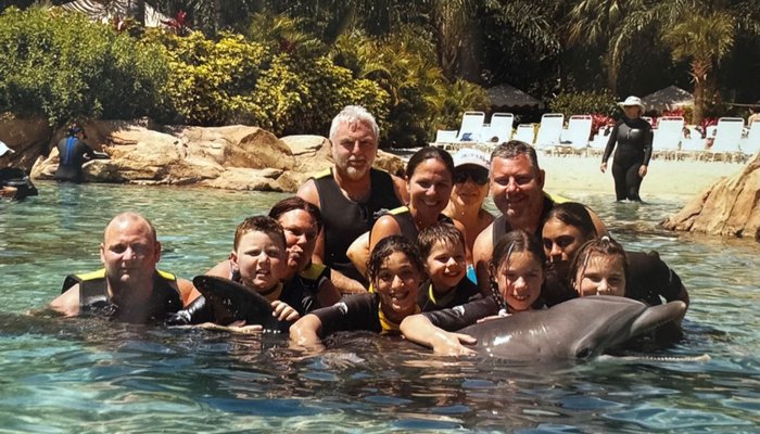Derrick and Sue pose with their family of 10 young people and a dolphin!