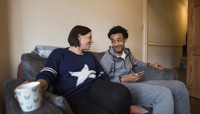 Foster carer with teenager chatting on a couch