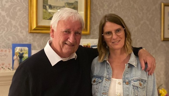 Foster parent Karen and her father Sam stood in living room together and smiling 2