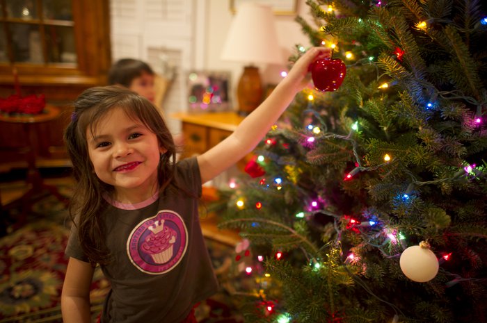 Little girl putting bauble on Christmas tree