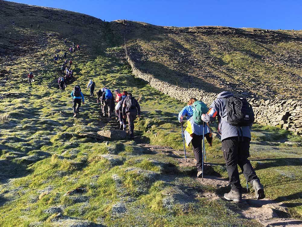 Group of hikers climb up a large hill