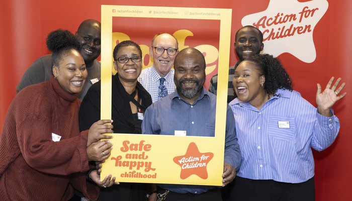 group of people standing with an action for children instagram frame cutout