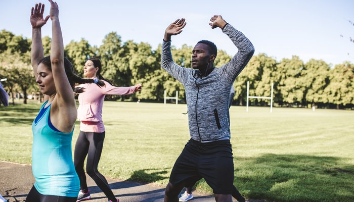 Group of young adults in the park going jumping jacks