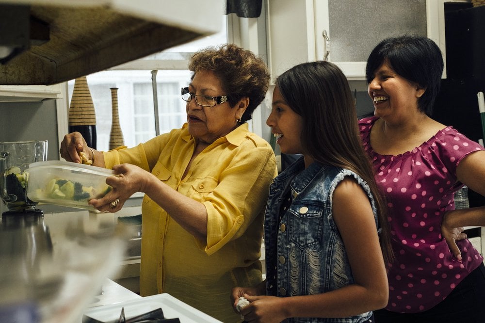Happy women showing younger girl how to cook in the kitchen.jpg