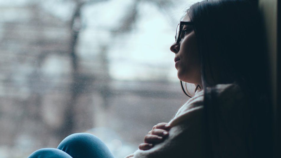 Sad teen girl looks out of the window