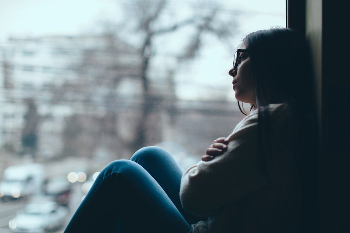 Sad teen girl looks out of the window