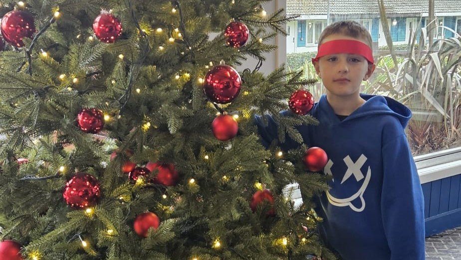 Joel, a child we've supported, standing next to a Christmas tree