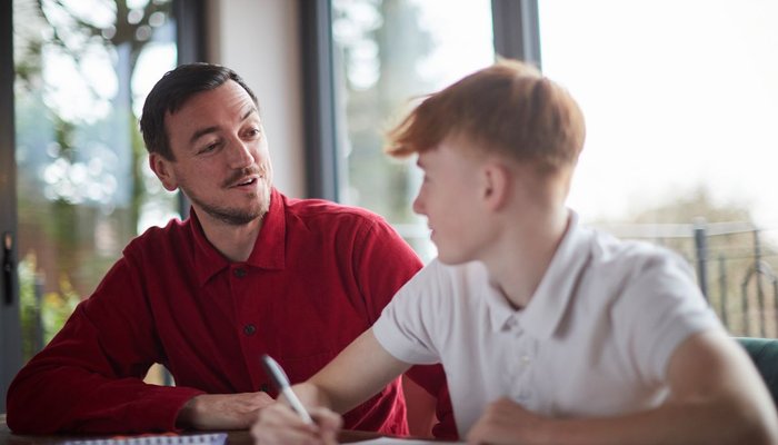 Man helping boy with homework and smiling