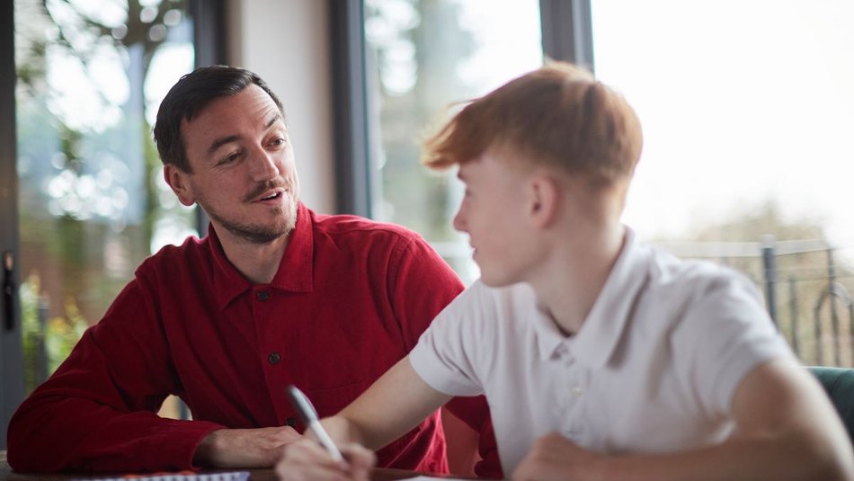 Man helping boy with homework and smiling