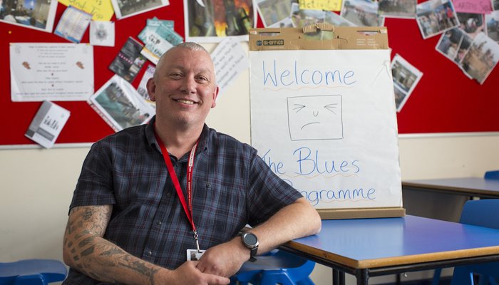 man in front of blues programme sign.jpg