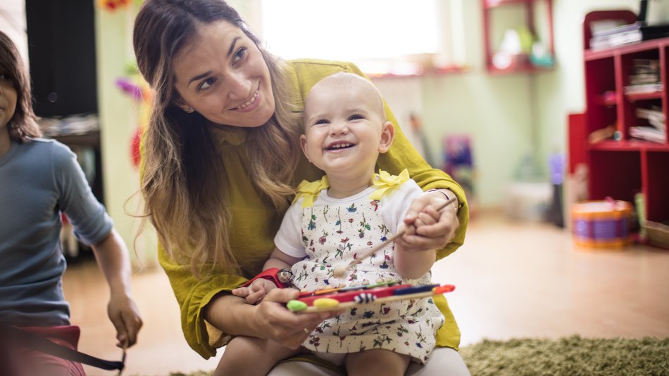 Mother and baby in a playgroup smiling and playing on a xylophone