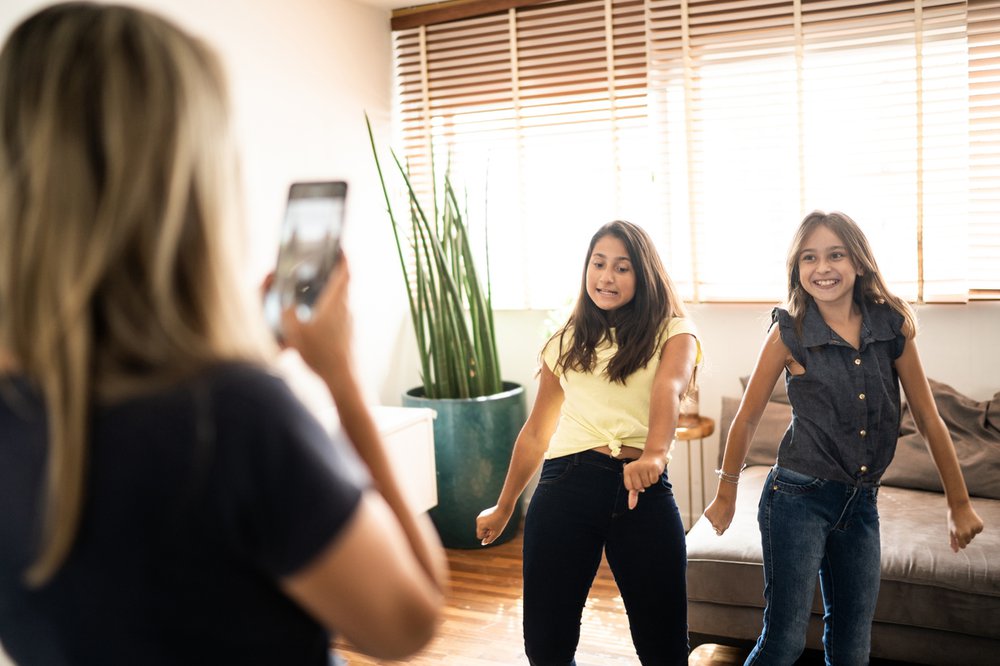 Mother films two teen daughters making a dance video at home