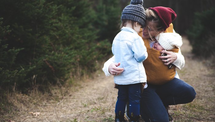 Mother with baby kneeling down to comfort daughter