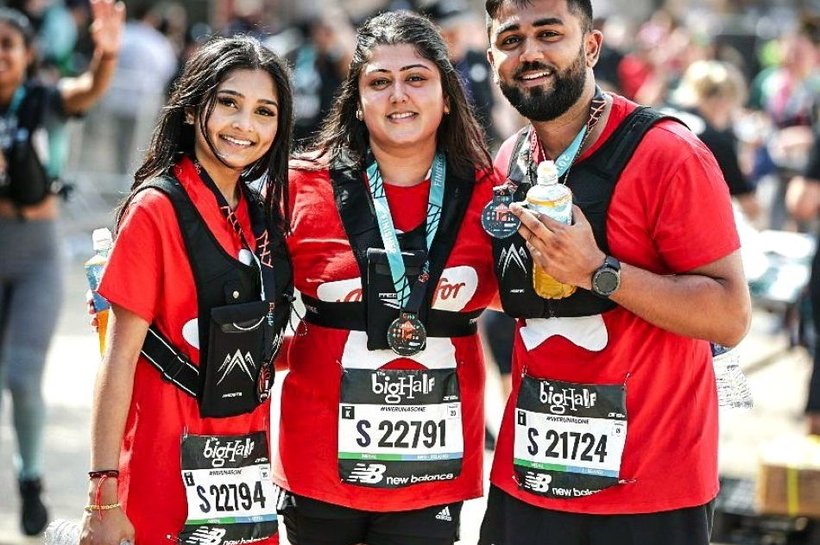 Three people smiling at the camera. They have just completed a half marathon and are wearing medals around their neck.