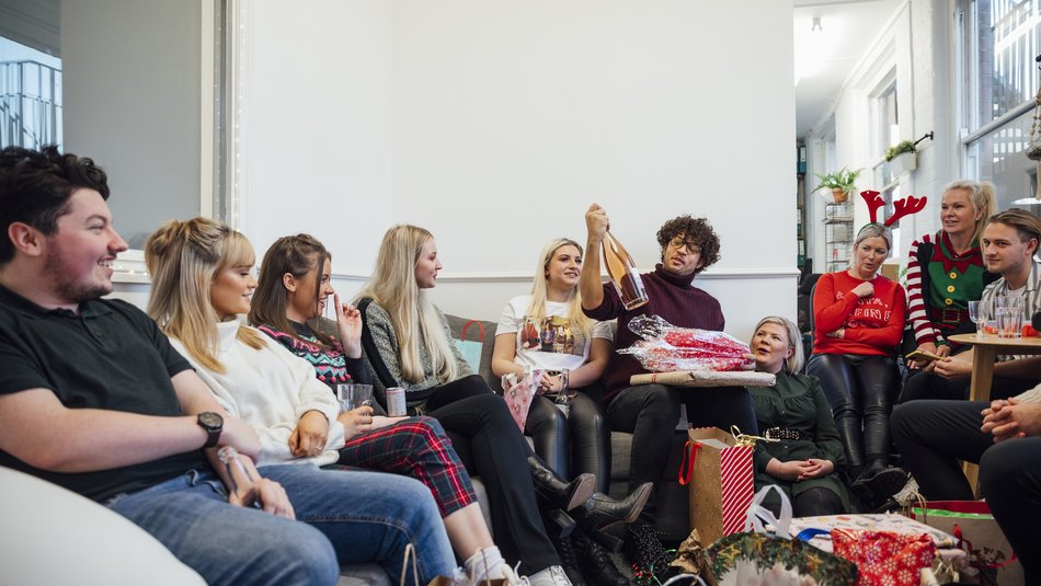 Office staff enjoying a Christmas party together, unwrapping gifts as part of secret Santa