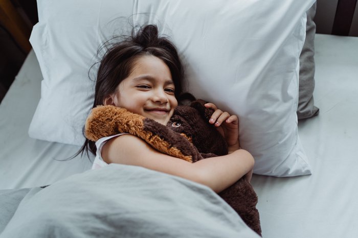 Girl in bed hugging teddy