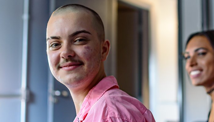 Portrait of a non-binary person smiling looking into the camwera and a transgender woman looking at the them