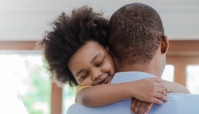 Portrait of father and son hugging laughing in living room