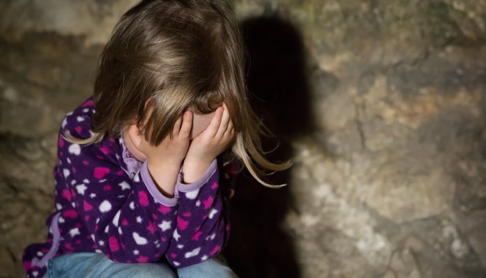 Sad young child covering face