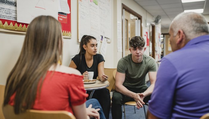 Small group o teenagers are talking to a mental health professional in a support group at the community centre