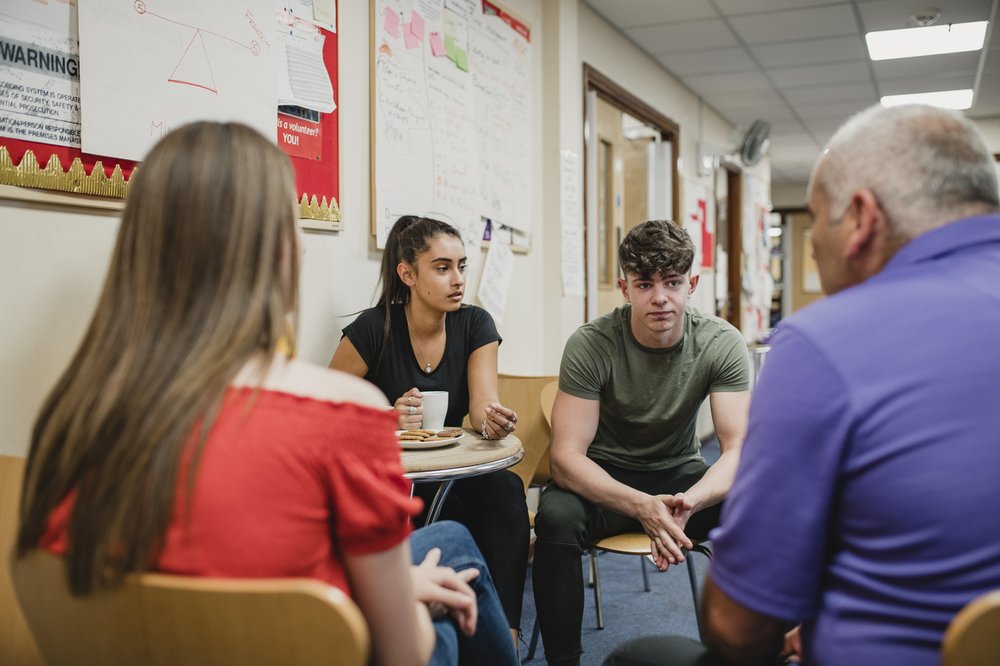 Small group o teenagers are talking to a mental health professional in a support group at the community centre