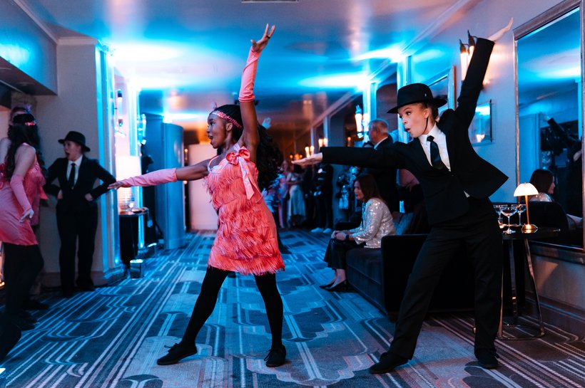 Cast members dancing, in classic 1920's themed costume