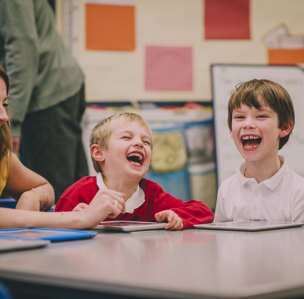 Students and teacher are laughing and enjoying themselves during a digital tablet lesson at school