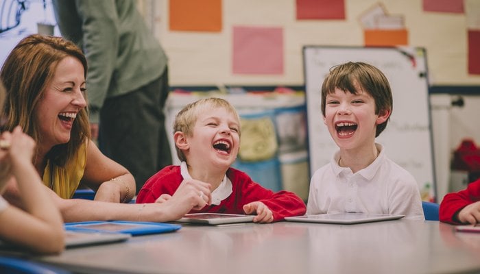 Students and teacher are laughing and enjoying themselves during a digital tablet lesson at school