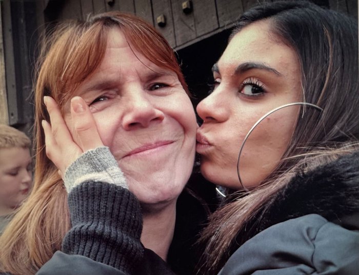 Sapphire kisses Sue on the cheek while they both long at the camera