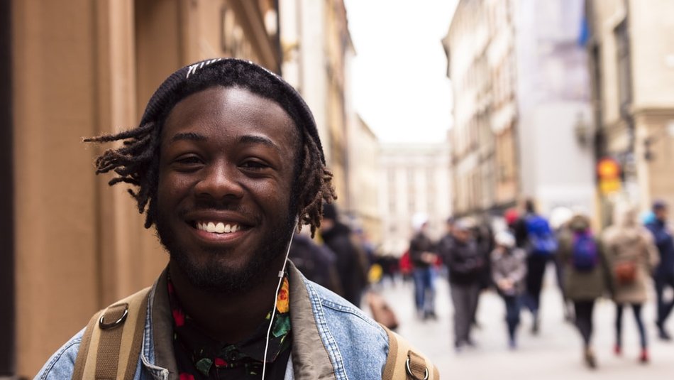 Teenage boy wearing headphones walking down crowded city street