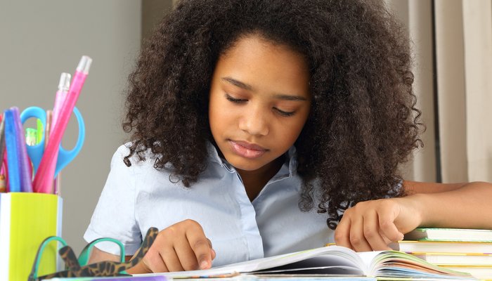 Teenage girl sitting at desk studying school books